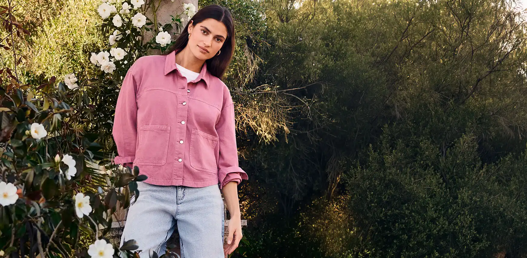 Roze overhemdblouse met knopen en zakken gecombineerd met wit T-shirt en lichte jeans voor een zomerse look.