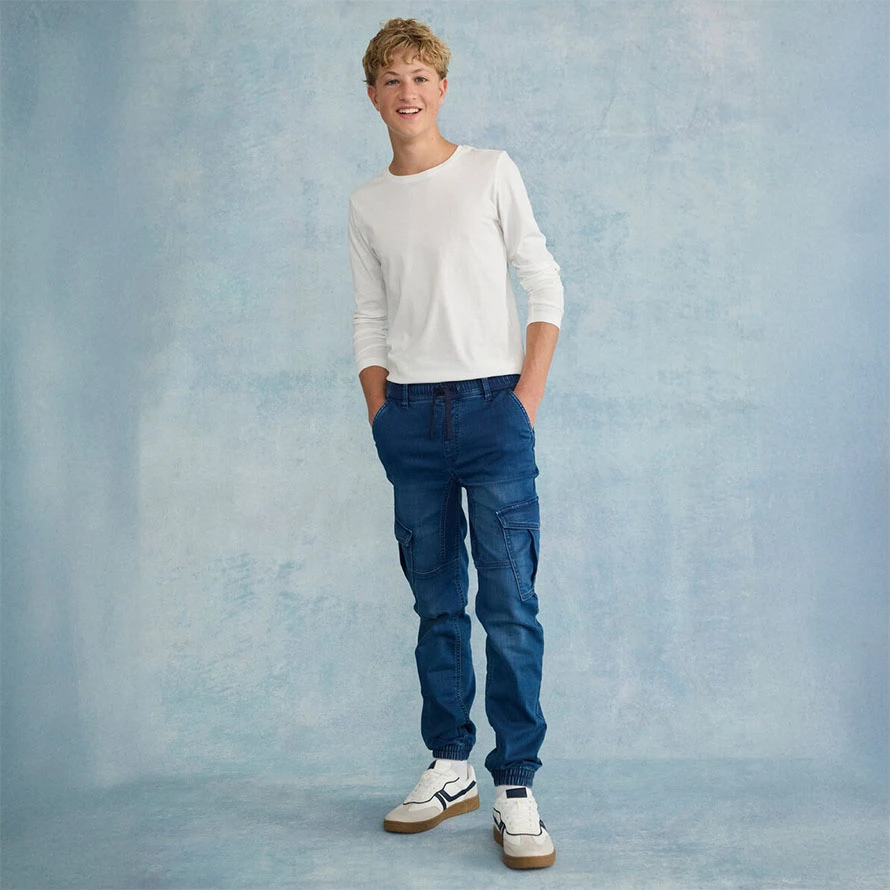 Casual look: witte trui met blauwe jeans en witte sneakers.
