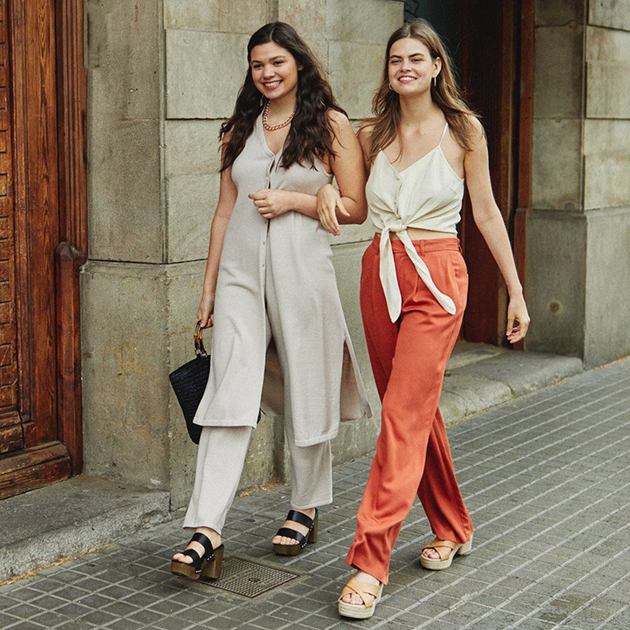 Zomers en elegant: lichte broekpakken en soepele tops gecombineerd met oranje broek en espadrilles.