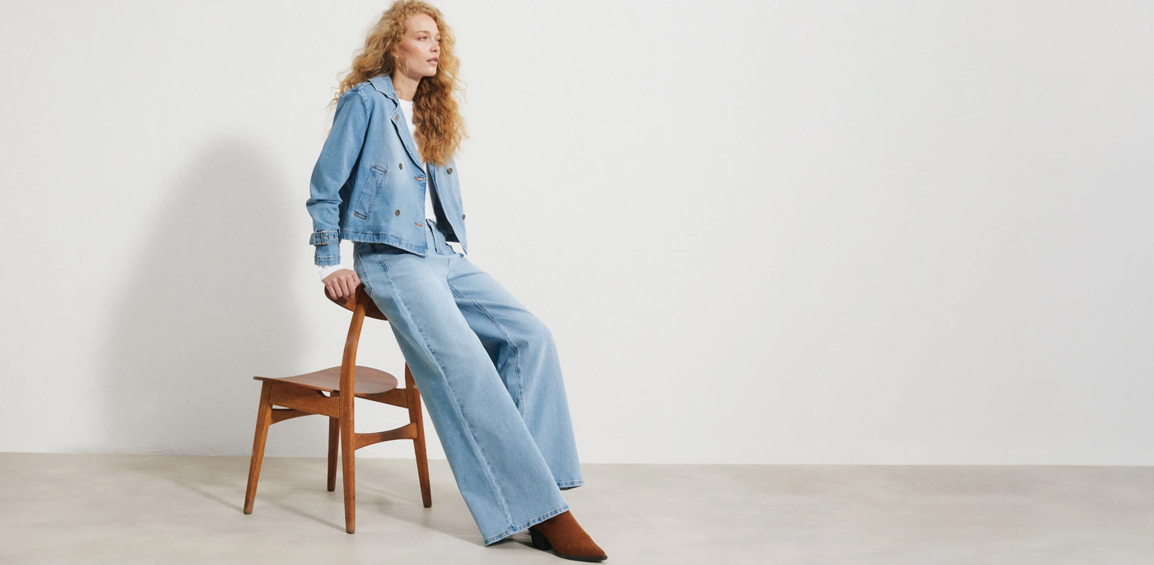 "Donkerblauwe Wide‑Leg jeans met een hoge taille en een brede, losvallende pijp, gemaakt van glad denim, gecombineerd met een wit T‑shirt, een donkerblauwe blazer en witte sneakers."