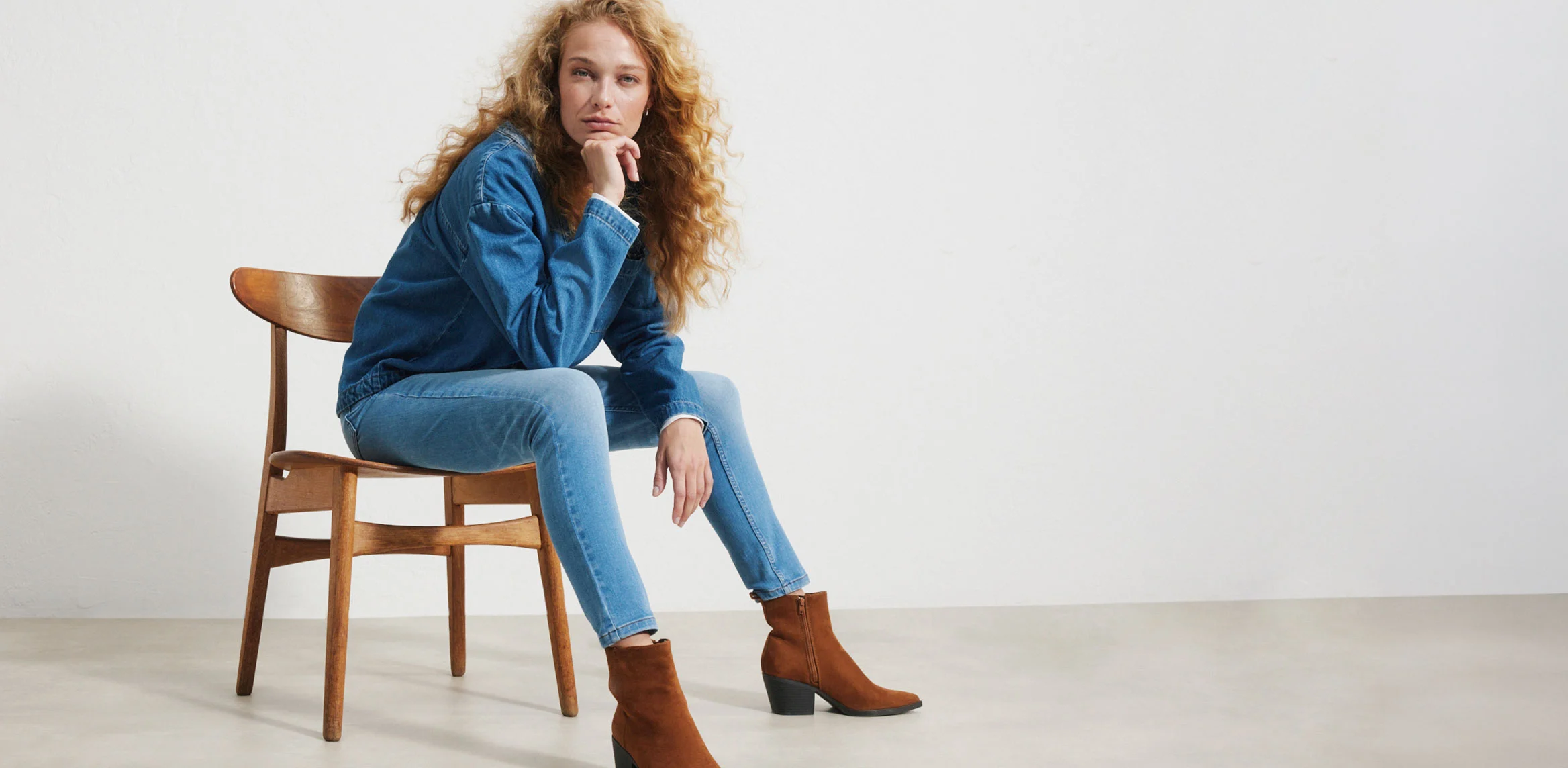 "Donkerblauwe Skinny‑Fit jeans, nauw aansluitend over de hele lengte en gemaakt van elastisch denim, gecombineerd met een wit, aansluitend T‑shirt, een beige jas en bruine loafers."