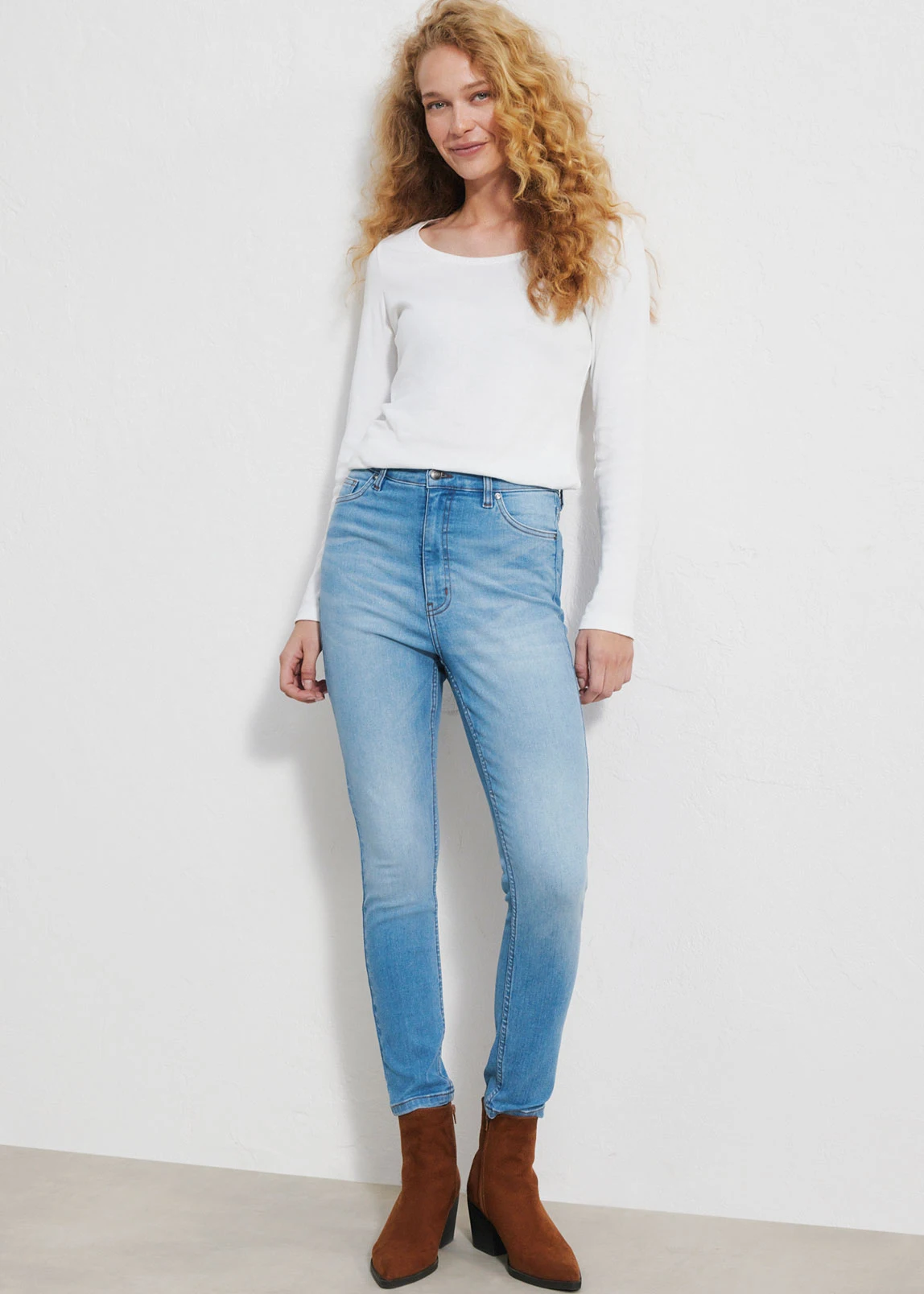 "Donkerblauwe skinny‑jeans met een aansluitende pasvorm, een klassiek vijfzakkenontwerp en een strakke afwerking, gecombineerd met een witte top en bruine schoenen."
