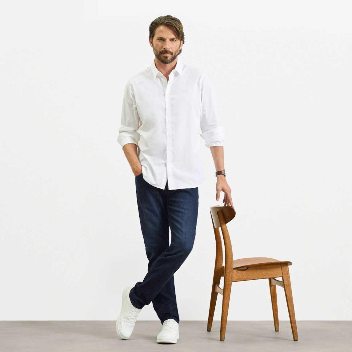 Wit overhemd, donkere Slim Fit jeans en witte sneakers.