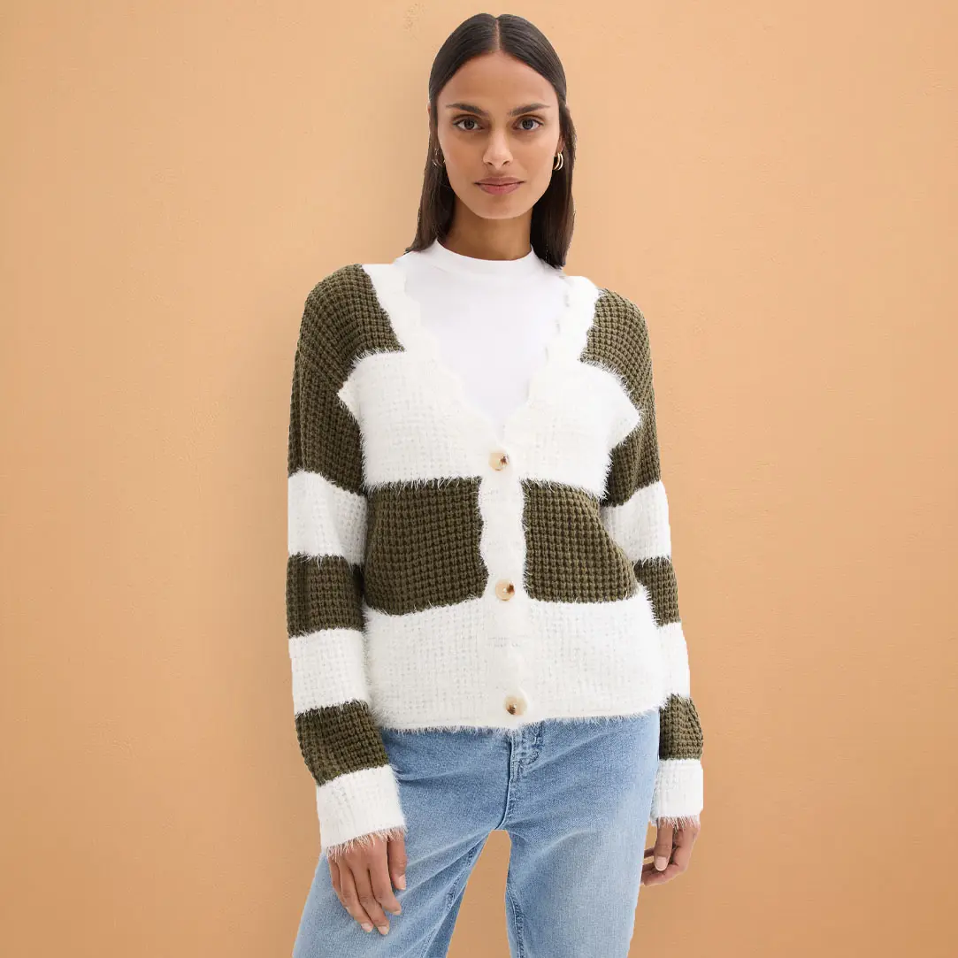 Gebreid vest in wit en olijfgroen gecombineerd met lichtblauwe jeans.