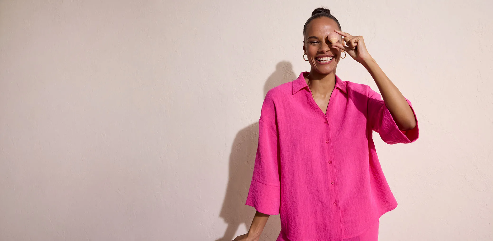 Vrouw draagt roze blouse met klassieke kraag en knoopsluiting.